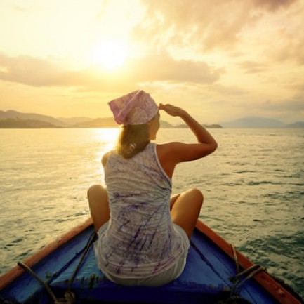 A happy sailing girl Catching sunset on a bow. We see her from the back.