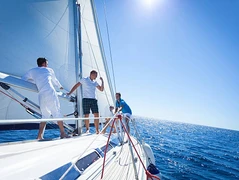 three sailors men on a sailboat with blue sky in the background