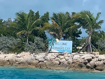 Sign with palm trees: Welcome to Normans cay. stopover for the sailing adventure