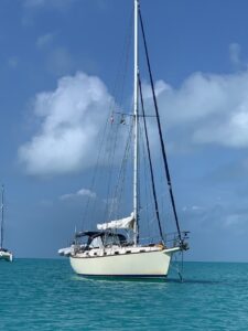 Sailboat anchored on blue water with cloudy sky
